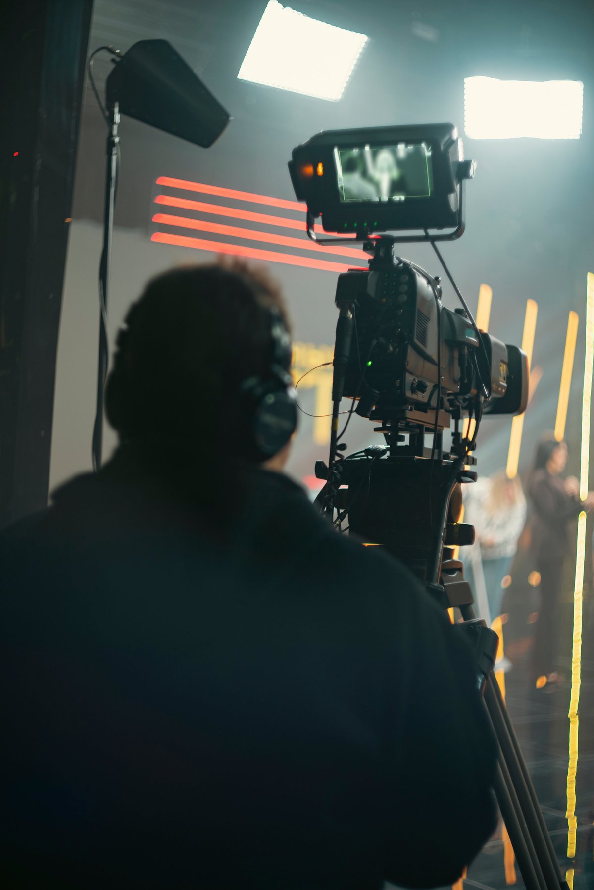 Camera operator filming professional video content on a tripod in a studio